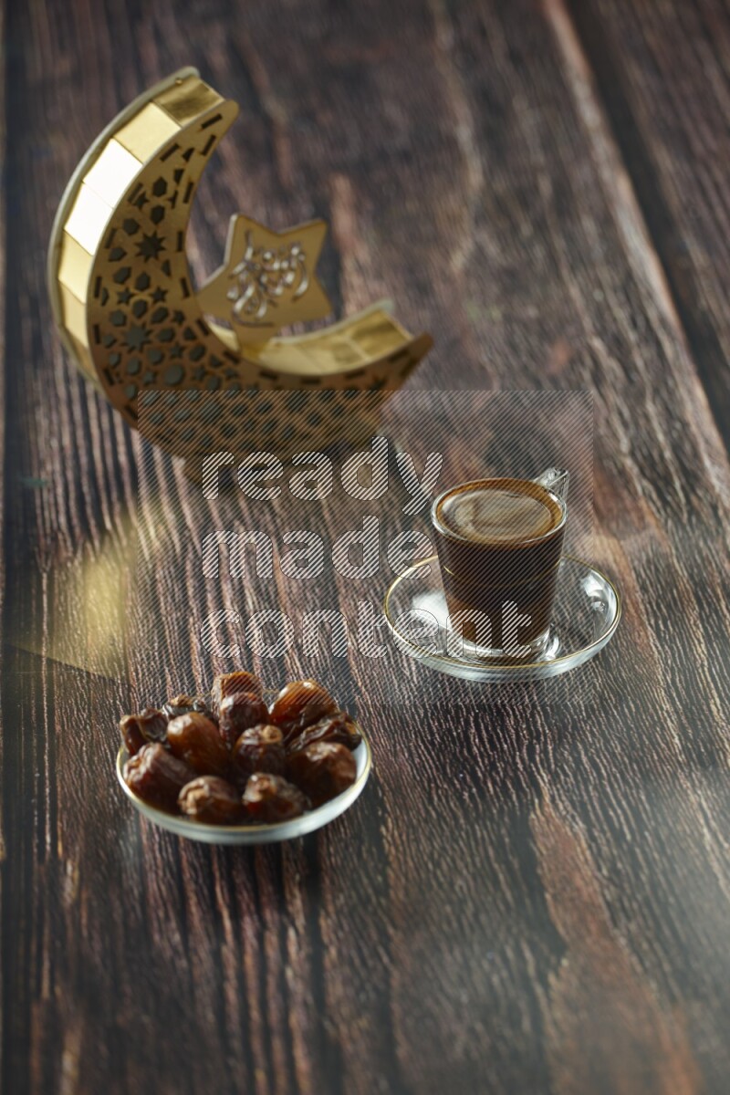 A wooden golden crescent lantern with different drinks, dates, nuts, prayer beads and quran on brown wooden background