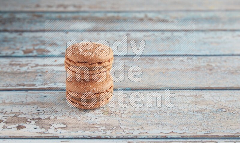 45º Shot of two Brown Hazelnuts macarons on light blue wooden background