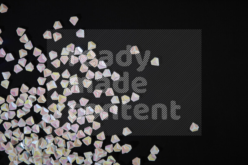 Colorful plastic shards for decoration scattered on a black background