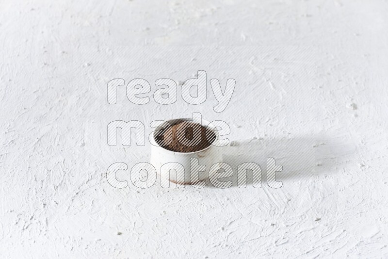 وعاء بيج من السيراميك ممتلئ ببودرة القرنفل علي خلفية بيضاء