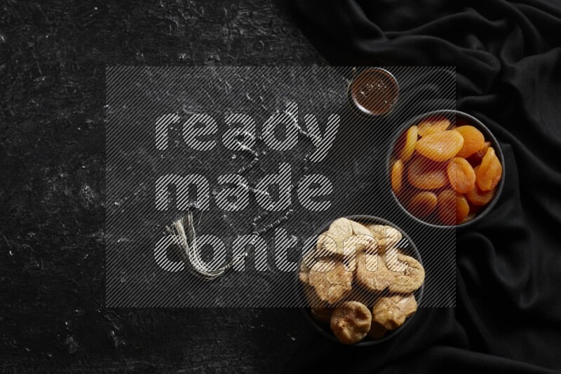 Dried fruits in pottery bowls with coffee in a dark setup