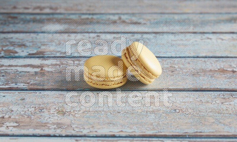 45º Shot of two Yellow Vanilla macarons on a light blue wooden background