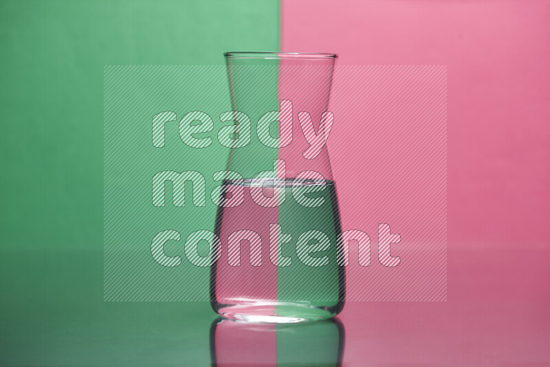 The image features a clear glassware filled with water, set against green and pink background