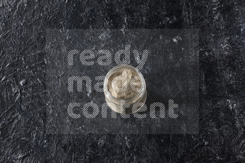 وعاء زجاجي مليء ببودرة الفلفل الأبيض على أرضية سوداء