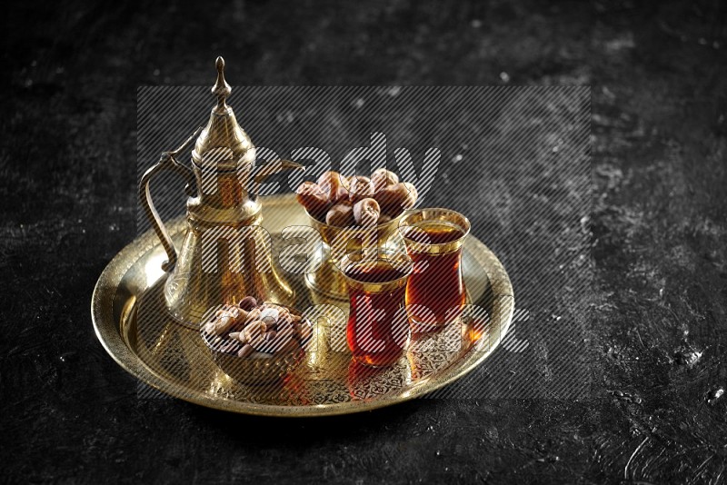 Nuts with dates and a drink on a metal tray in a dark setup