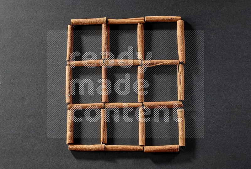 9 empty squares of cinnamon sticks on black flooring
