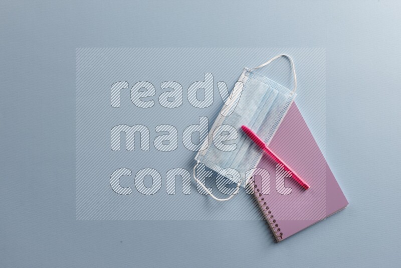 A purple notebook with different school supplies on blue background