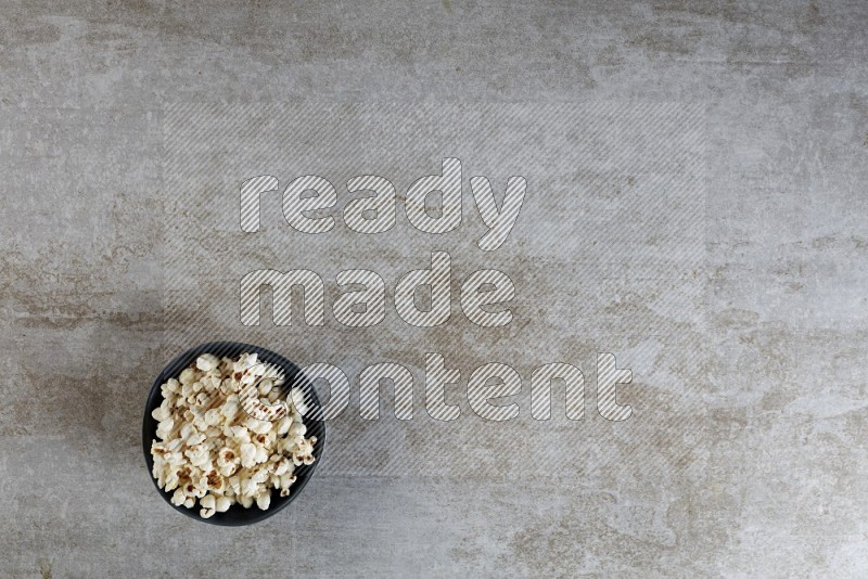 popcorn in black bowl on a grey textured countertop