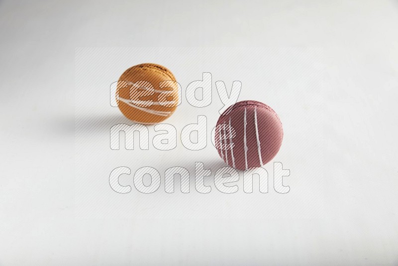 45º Shot of of two assorted Brown Irish Cream, and Red Poppy Flower macarons on white background