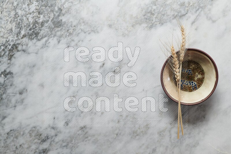 Wheat stalks on decorative pottery plate on grey marble background