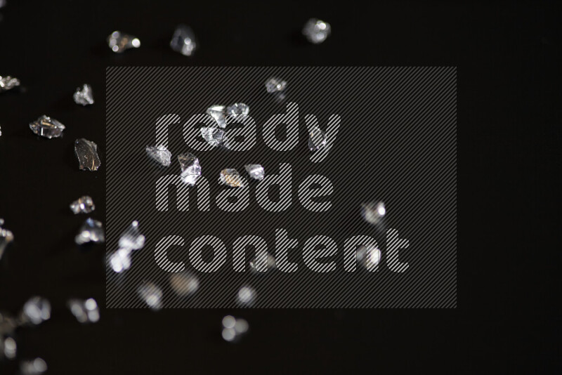 قطع زجاجية فضية لامعة متناثرة على خلفية سوداء