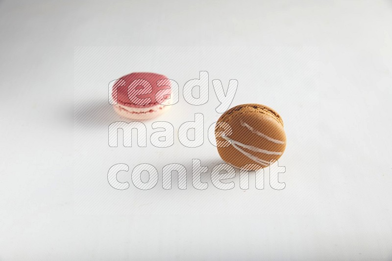 45º Shot of of two assorted Brown Irish Cream, and Pink Litchi Raspberry macarons on white background