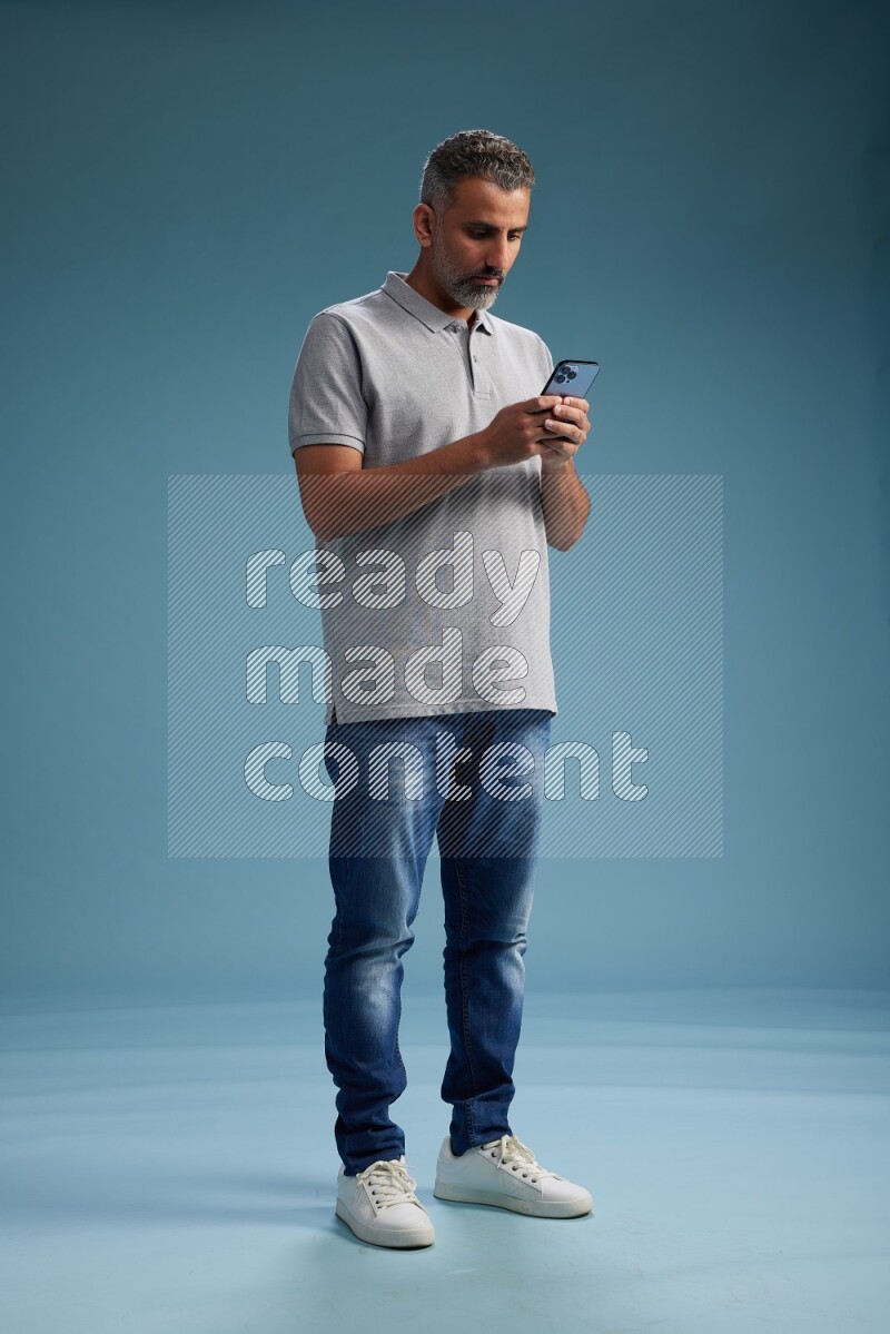Man Standing texting on phone on blue background
