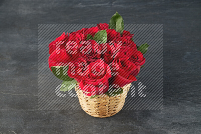 Vibrant red roses in a wicker basket on black marble background