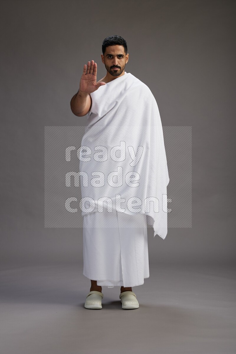 A man wearing Ehram Standing Interacting with the camera on gray background