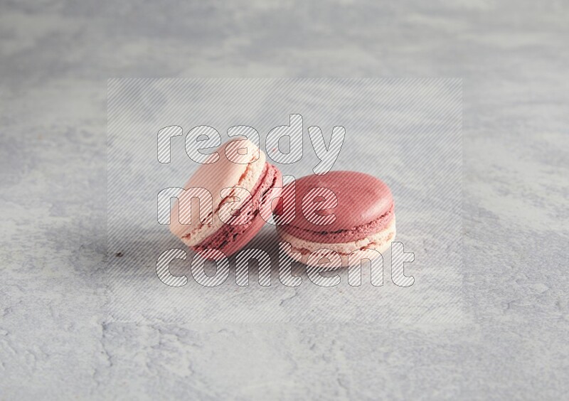 45º Shot of two Pink Litchi Raspberry macarons  on white  marble background