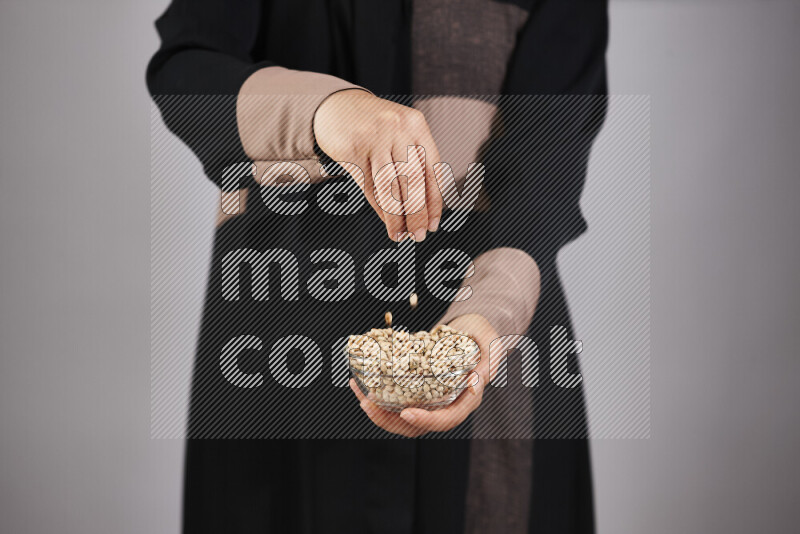 Woman in abaya holding different kinds of legumes in different positions