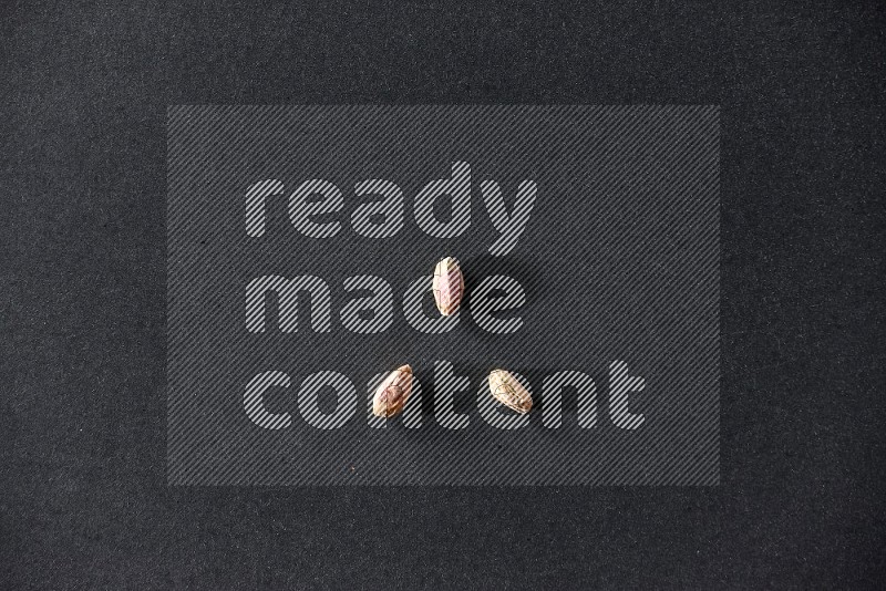 3 peeled pistachios on a black background in different angles