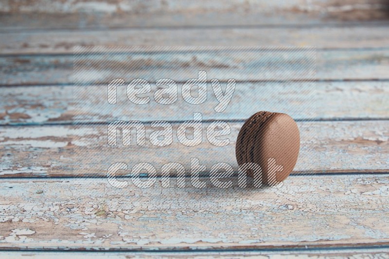 45º Shot of Brown Dark Chocolate macaron on light blue wooden background