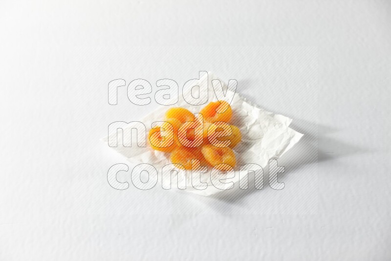 Dried apricots on a crumpled piece of paper on a white background in different angles