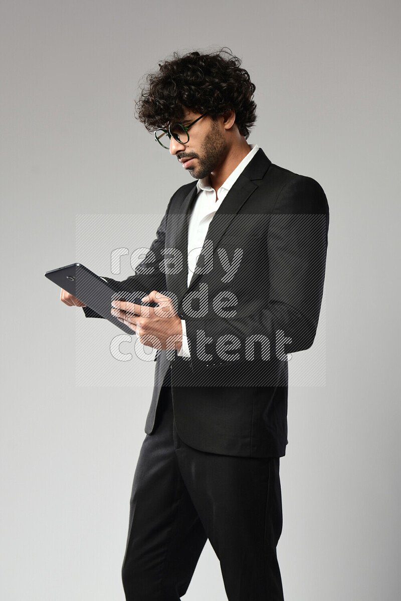 A man wearing formal standing and browsing on a tablet on white background