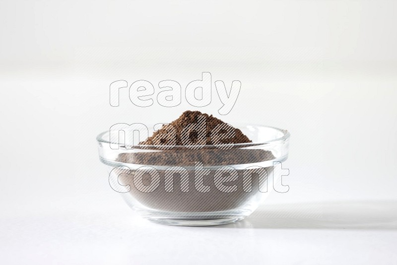 A glass bowl full of cloves powder on white flooring