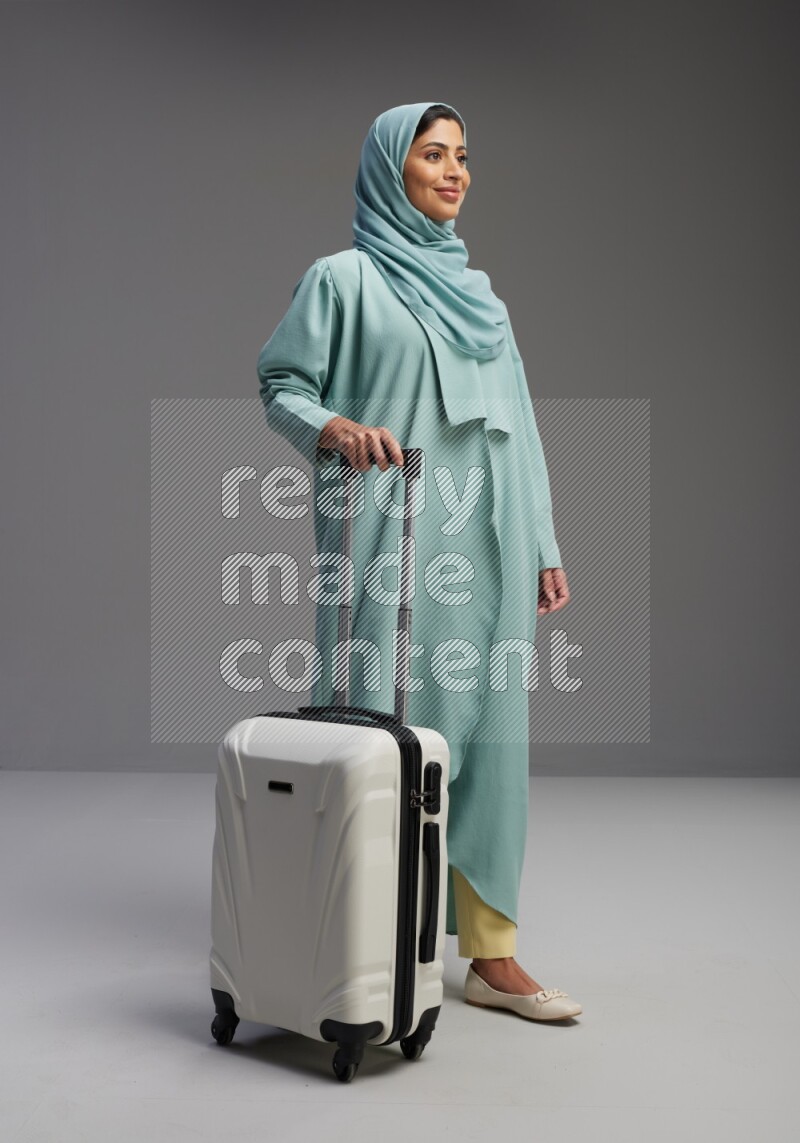 Saudi Woman wearing Abaya standing holding Travel bag on Gray background
