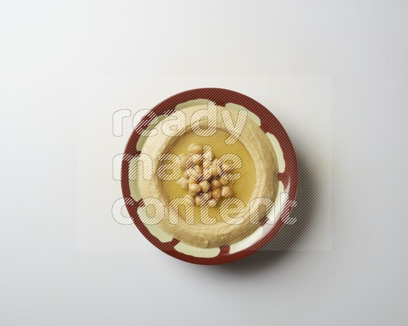 Hummus in a traditional plate garnished with roasted chickpeas  on a white background