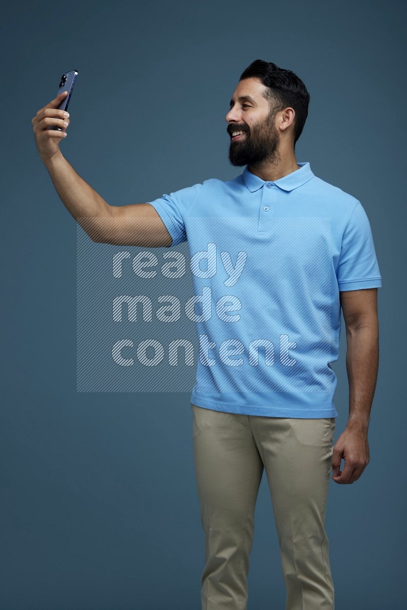 Man Taking a Selfie in a blue background wearing a Blue shirt