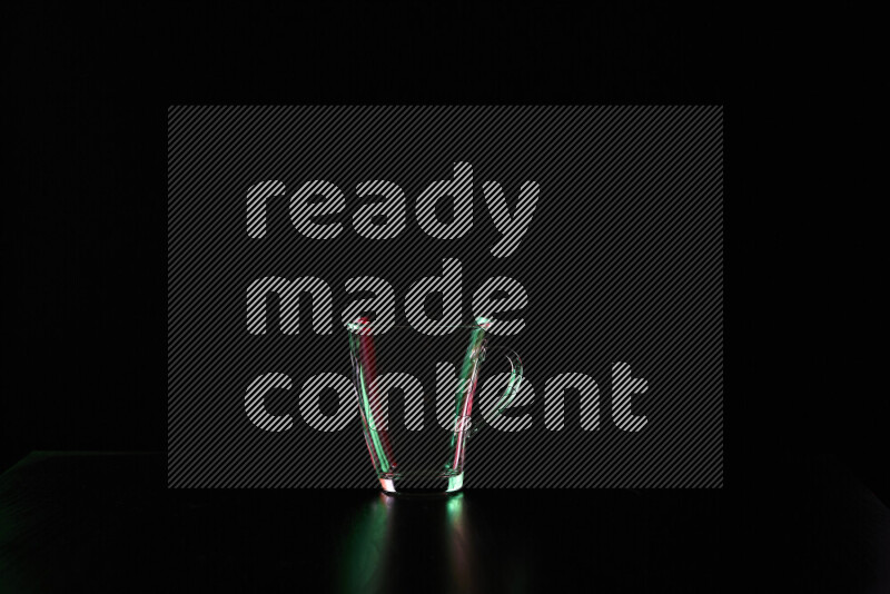 Glassware with rim light in red and green against black background