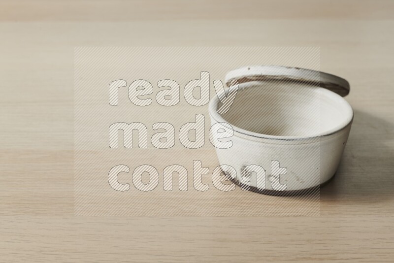 A white pottery bowl on light wooden background