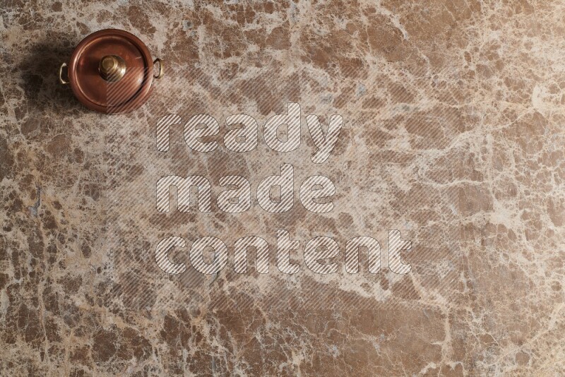 A small copper pot on beige marble background
