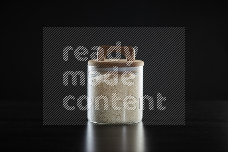 White rice in a glass jar on black background