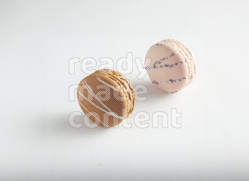 45º Shot of of two assorted Brown Irish Cream, and pink orange blossom macarons on white background