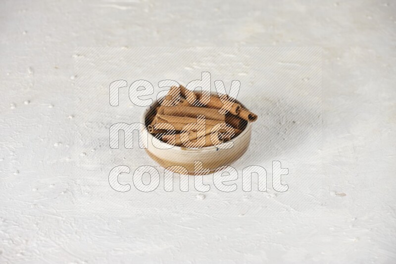Cinnamon sticks in a ceramic bowl in different angles on white background