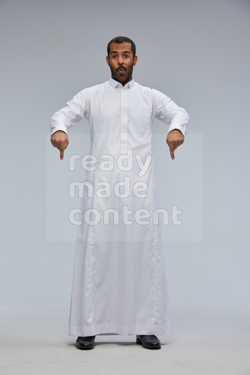 Saudi man Wearing Thob standing interacting with the camera on Gray background