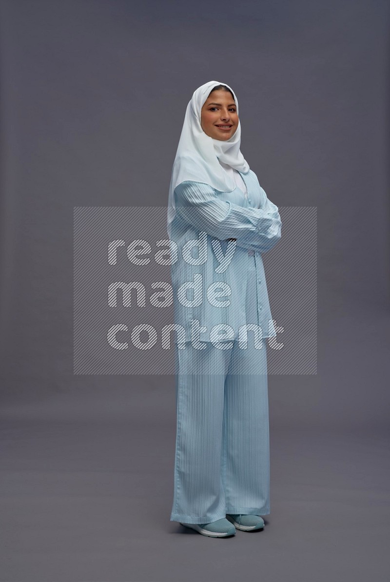 Saudi woman wearing hijab clothes standing with crossed arms on gray background