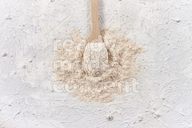A wooden spoon full of onion powder on white background