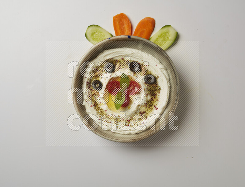 Lebnah garnished with cherry tomato, mint, olives & pine nuts in a grey pottery plate on a white background