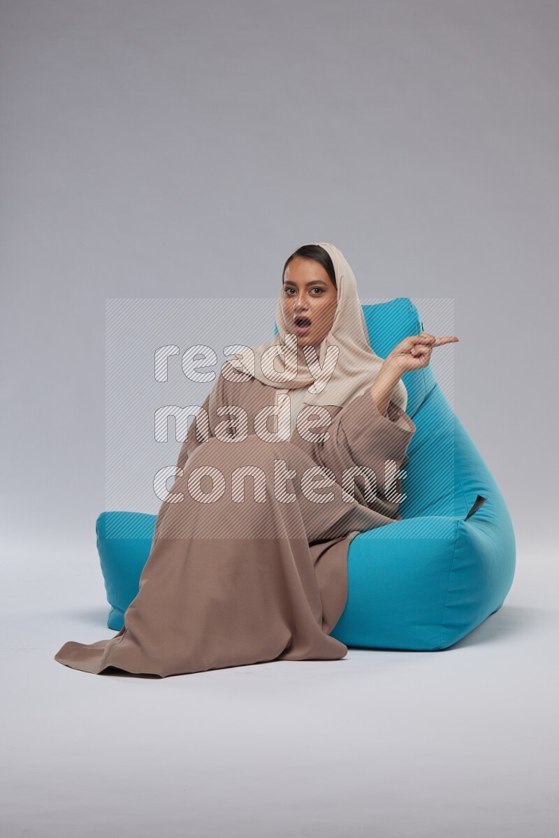 A woman sitting on a blue beanbag and interacting with the camera