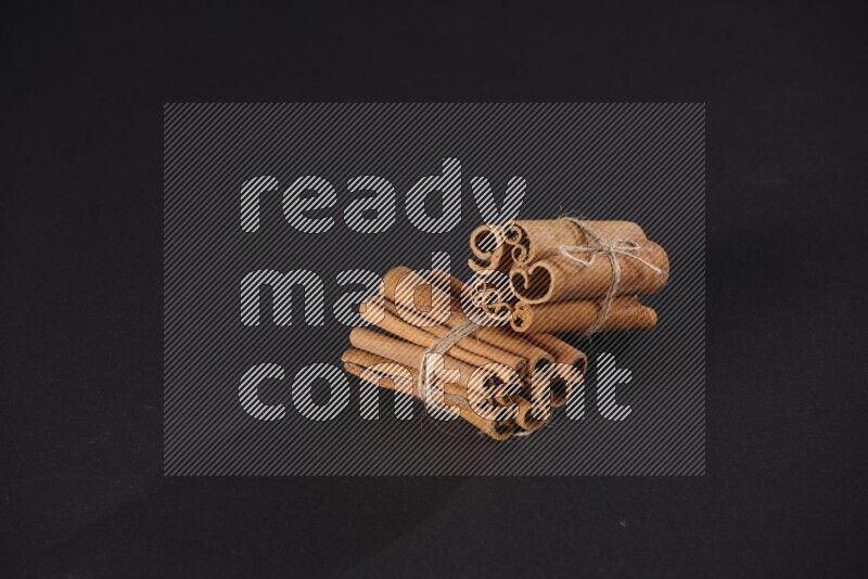 Two bounded stacks of cinnamon sticks on black background