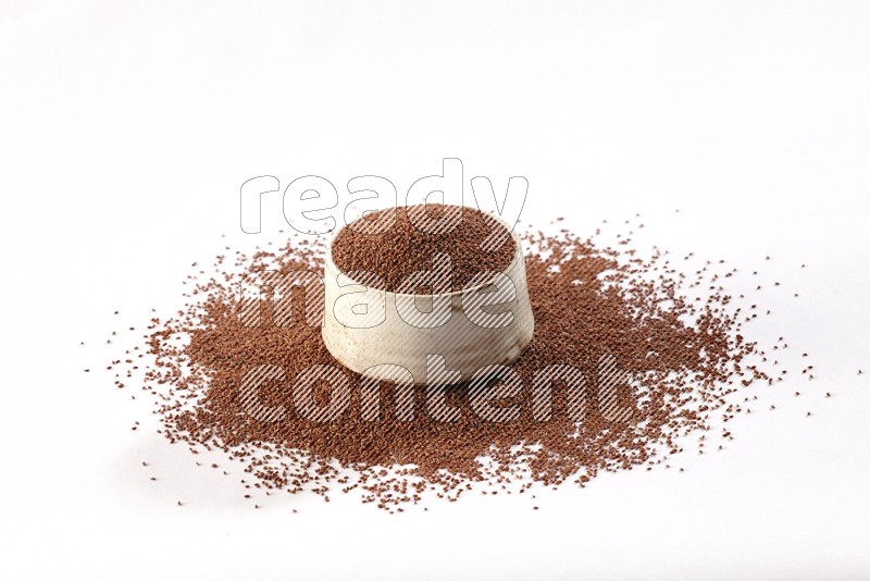 A beige pottery bowl full of garden cress seeds with more seeds spread on a white flooring