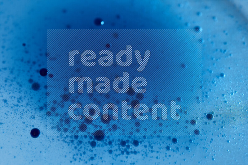 Close-ups of abstract blue watercolor drops on oil Surface on blue background