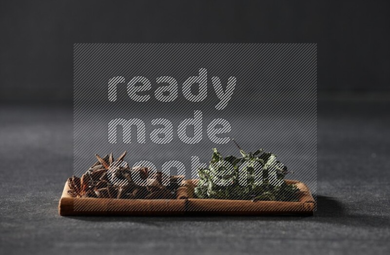 مربعان من أعواد القرفة ممتلئان باليانسون النجمي والنعناع المجفف علي خلفية سوداء