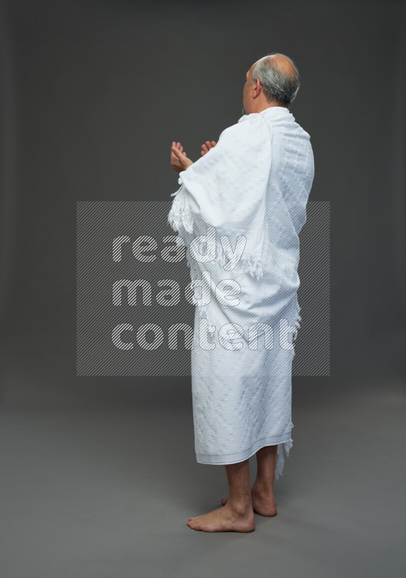 A man wearing Ehram Standing dua'a on gray background