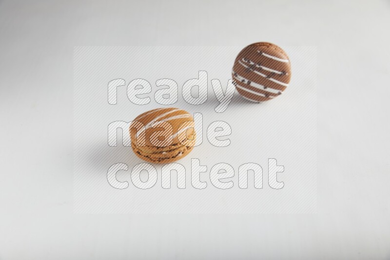 45º Shot of of two assorted Brown Irish Cream, and Brown white Chocolate Caramel macarons on white background
