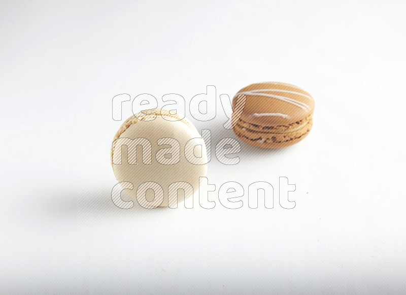 45º Shot of of two assorted Brown Irish Cream, and White Caramel fleur de sel macarons on white background