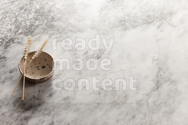 سنابل من القمح علي وعاء فخاري متعدد الألوان علي خلفية من الرخام الرمادي