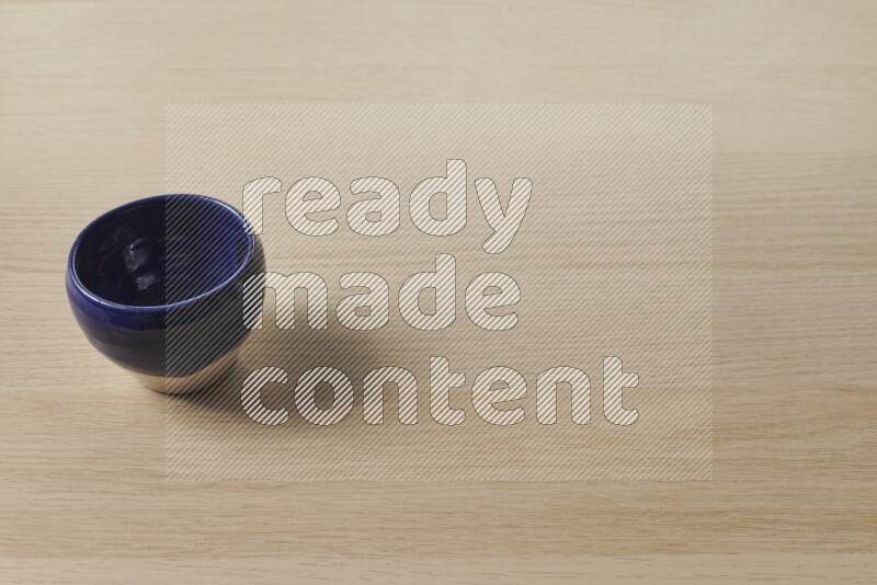 A multicolored pottery bowl on light wooden background