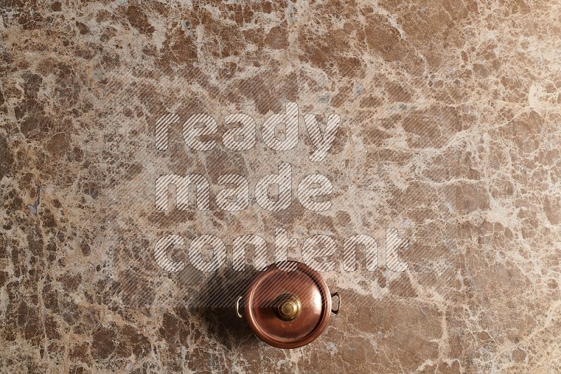 Top View Shot Of A Small Copper Pot On beige Marble Flooring